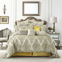 a bed with yellow and gray comforters in a room next to a mirror on the wall