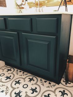 a bathroom vanity with black cabinets and white counter tops, in front of a tiled floor