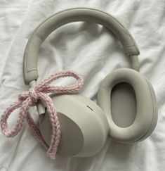 a pair of headphones laying on top of a white sheet with a pink cord