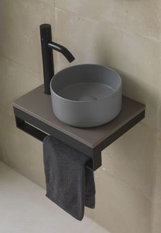 a bathroom sink with a black faucet and grey towel hanging from the wall