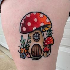 a woman's thigh with a mushroom house tattoo on it