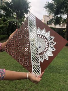 a woman holding an intricately designed piece of art in her hand on the grass