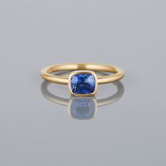 18K Yellow Gold Timeless Sapphire Ring With Bezel Setting, Blue Sapphire Ring With Bezel Setting, Gold Cushion Cut Sapphire Ring, Gold Sapphire Ring With Cushion Cut, Cushion Cut Sapphire Ring In Yellow Gold, Classic Sapphire Ring With Smooth Bezel For Anniversary, Yellow Gold Sapphire Ring With Cushion Cut, Timeless Blue Sapphire Ring, Classic Tanzanite Solitaire Sapphire Ring