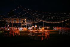 an outdoor wedding reception with string lights and tables set up for the guests to eat