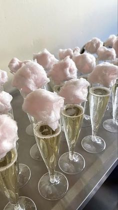 there are many champagne flutes with pink flowers in them on the table and one is filled with cotton balls