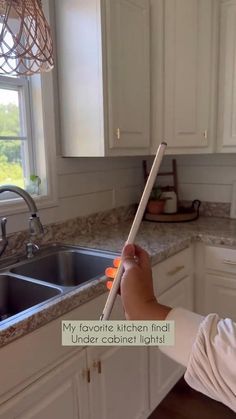 a person holding a stick in their hand over a kitchen sink with the words, my favorite kitchen find under cabinet lights