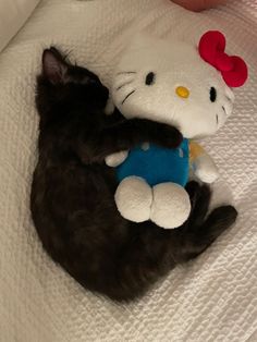 a hello kitty stuffed animal laying on top of a bed next to a teddy bear