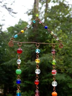 a wind chime hanging from a tree with lots of different colored beads on it