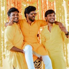 three men in yellow are posing for the camera