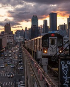 an image of a train going down the tracks in front of a cityscape