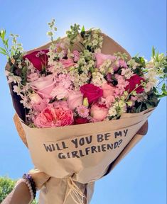 a bouquet of pink and white flowers in a paper bag with the words will you be my girlfriend?