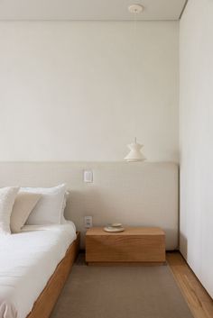 a white bed sitting next to a wooden night stand