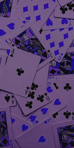 a pile of purple playing cards sitting on top of each other in different shapes and sizes