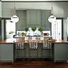 a kitchen with green cabinets and an island in the middle is surrounded by stools