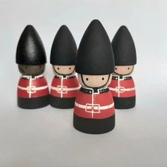 four wooden toy soldiers are lined up in red and black uniforms, with one soldier standing out from the crowd