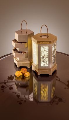 two small candles sitting on top of a table next to some oranges and boxes