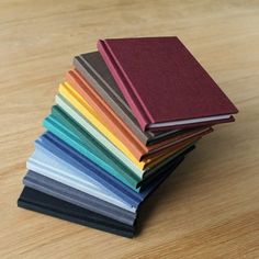 a stack of books sitting on top of a wooden table next to each other with different colors