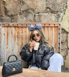 a woman sitting at a table with a handbag and cup in front of her