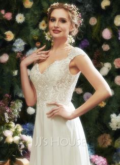 a woman in a white dress standing next to flowers