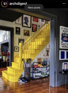 a yellow staircase in a home with pictures on the wall and wooden floors below it