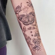 a woman's arm with a butterfly and flowers tattoo design on the left forearm