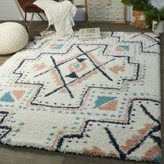 a white rug with blue, pink and orange designs on the floor next to a chair