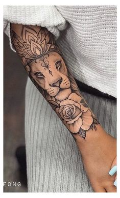 a woman's arm with a lion and roses tattoo on the left side of her arm