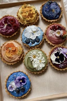 nine pies with flowers on them sitting in a box, ready to be eaten