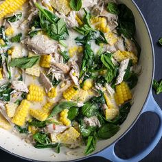 a skillet filled with chicken, corn and spinach on top of a table