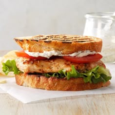 a grilled chicken sandwich with tomatoes, lettuce and mayonnaise on toasted bread