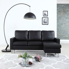 a living room with a black leather couch and large floor lamp in the corner next to it