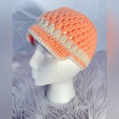 an orange and white crocheted hat on top of a mannequin head