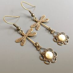 "Brass Dragonfly Earrings - Beautiful Filigrees with White Glass Pearls dangle from Antiqued Brass Dragonflies. The dragonflies are brass stampings. The design is only on one side. Antiqued Brass Earwires Earrings measure 2\" from top of earwires to bottom of filigree. For similar dragonfly filigree earrings: https://www.etsy.com/shop/mcstoneworks/search?search_query=dragonfly+filigree+earrings&order=date_desc&view_type=gallery&ref=shop_search For other dragonfly earring styles: http Woman Birthday, Earring Styles, Dragonfly Jewelry, Dragonfly Earrings, Filigree Earrings, Gift For Woman, Dragonflies, Animal Jewelry, Diy Earrings