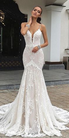 a woman in a white wedding dress standing on a brick walkway with her hand to her face