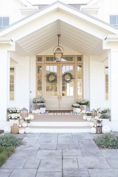 a white house with two front doors and wreaths