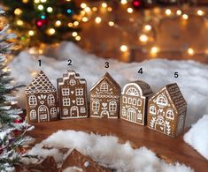 a group of gingerbread houses sitting on top of snow next to a christmas tree