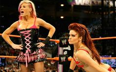 two women in costumes standing next to each other on a wrestling ring, one with her mouth open