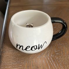 a white cup with a black handle that says meow