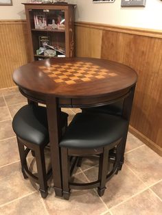 a wooden table with two black chairs and a checkered board on the back drop