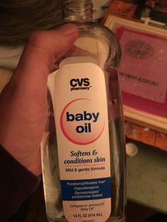 someone holding a bottle of baby oil in their hand