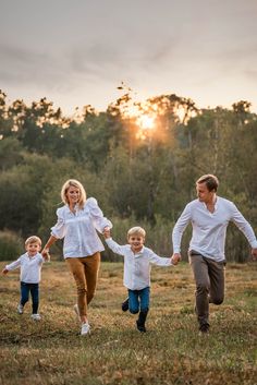 a family running through the grass with their hands in each other's pockets as the sun sets