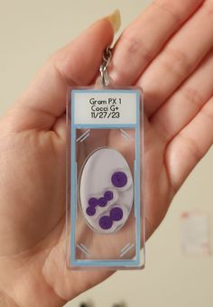 a hand holding a keychain with two purple buttons on it