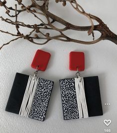 two square shaped earrings with black and white designs on them next to a tree branch