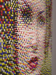 an art piece made out of many different colored beads on the side of a wall