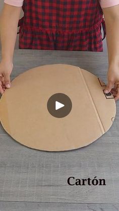 a person cutting out a cardboard circle on top of a wooden table with the word carton cut out