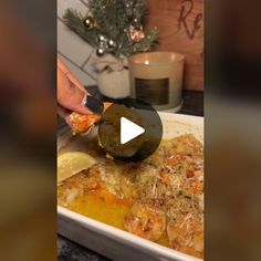 someone is cutting up some food in a white dish on a table with a christmas tree behind them