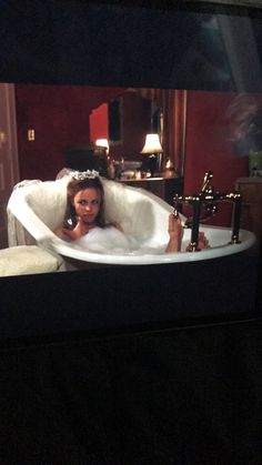 a woman laying in a bathtub holding a cell phone