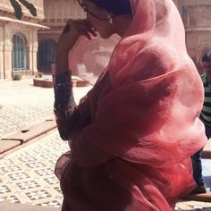 a woman in a pink hijab walking down the street