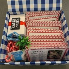 an open box filled with candy canes and other items on top of a blue and white checkered table cloth