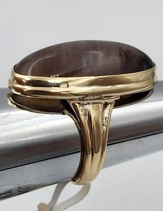 This is a 14k yellow gold ring set with a 26mm by 12mm oval smoky quartz. The ring is a size 6 and weighs 5.5 dwt. The quartz has color and pattern variations that did not show up very well in the pictures. Brown Oval Gemstone Rings, Classic Smoky Quartz Rings For Formal Occasions, Classic Oval Brown Ring, Classic Brown Oval Ring, Classic Formal Smoky Quartz Rings, Gold Oval Moonstone Ring For Formal Occasions, Brown Oval Cabochon Rings, Luxury Brown Oval Rings, Formal Brown Cabochon Rings